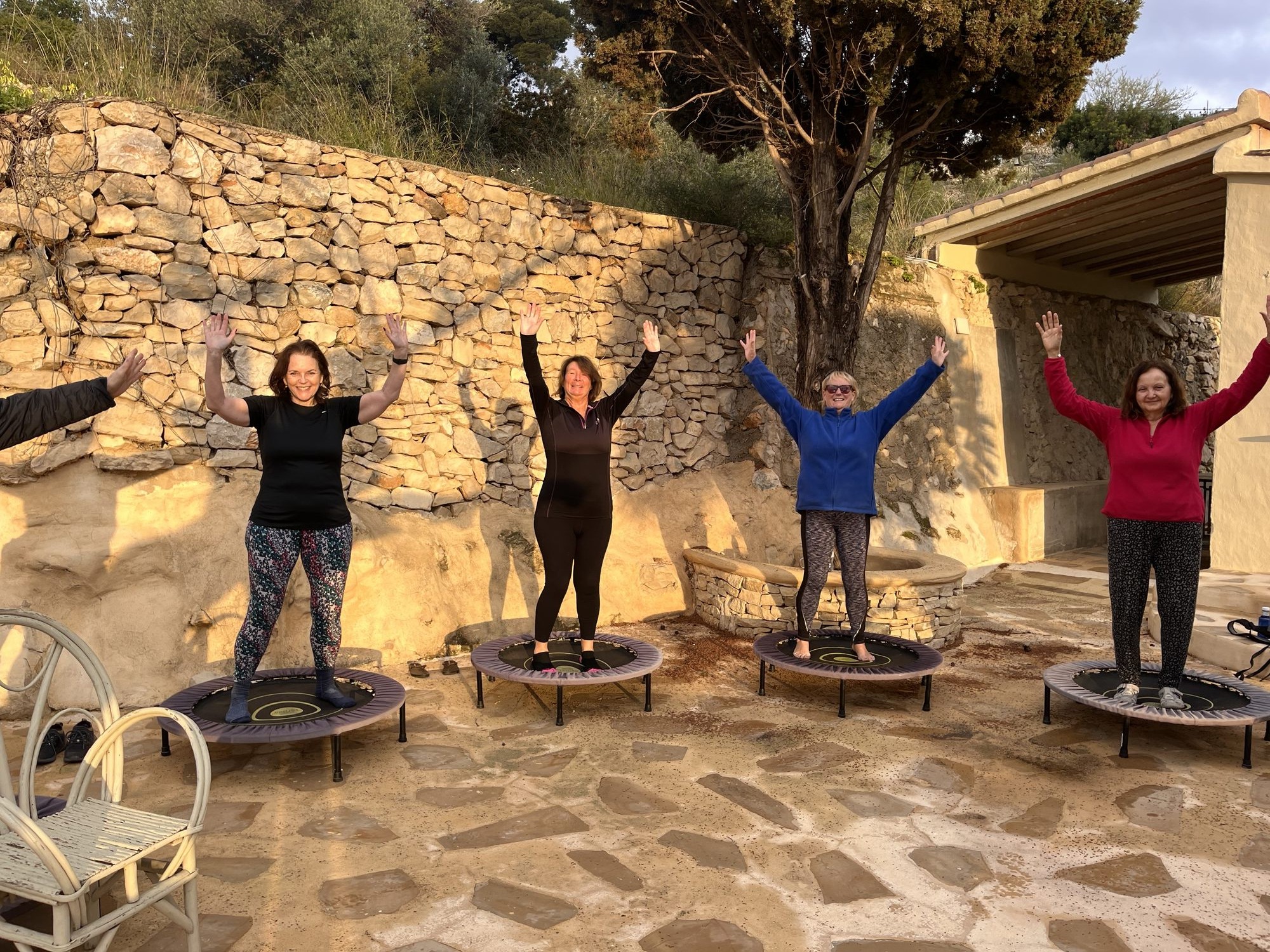 Four women upside down on mini-trampolines outdoors.