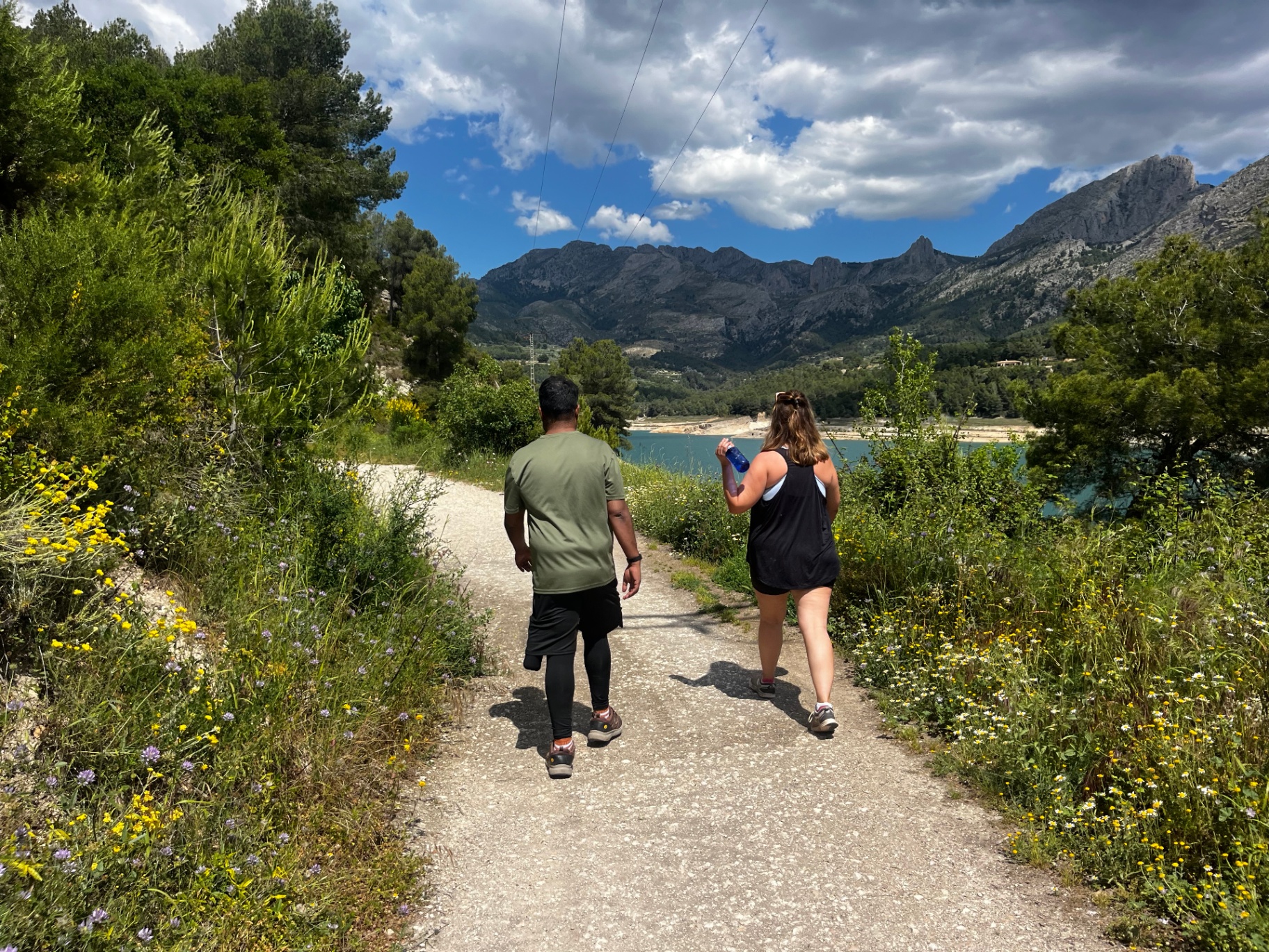 Guests walking along a scenic trail near a lake at Sana Sana Retreat in Spain